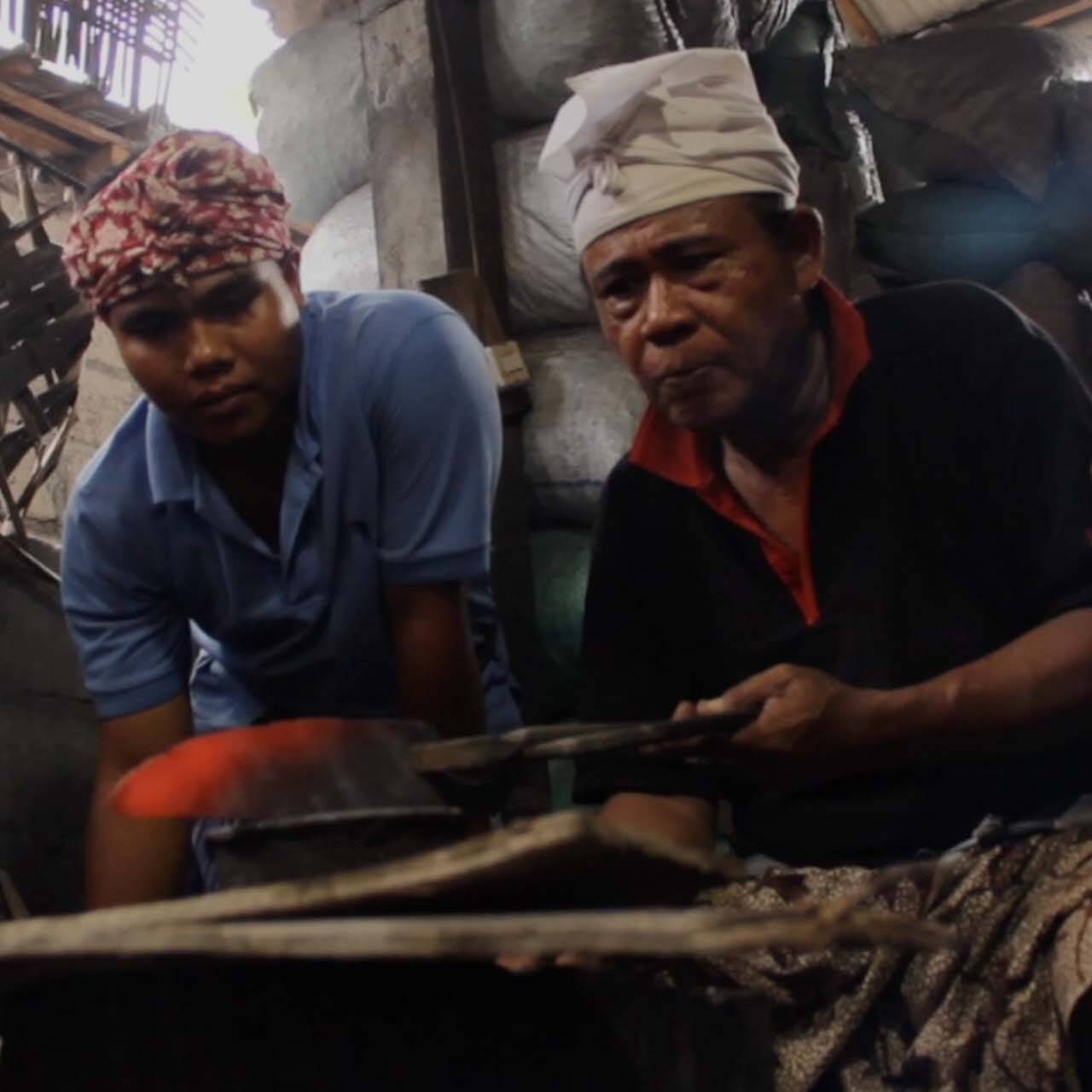 Two blacksmiths crafting a traditional keris dagger