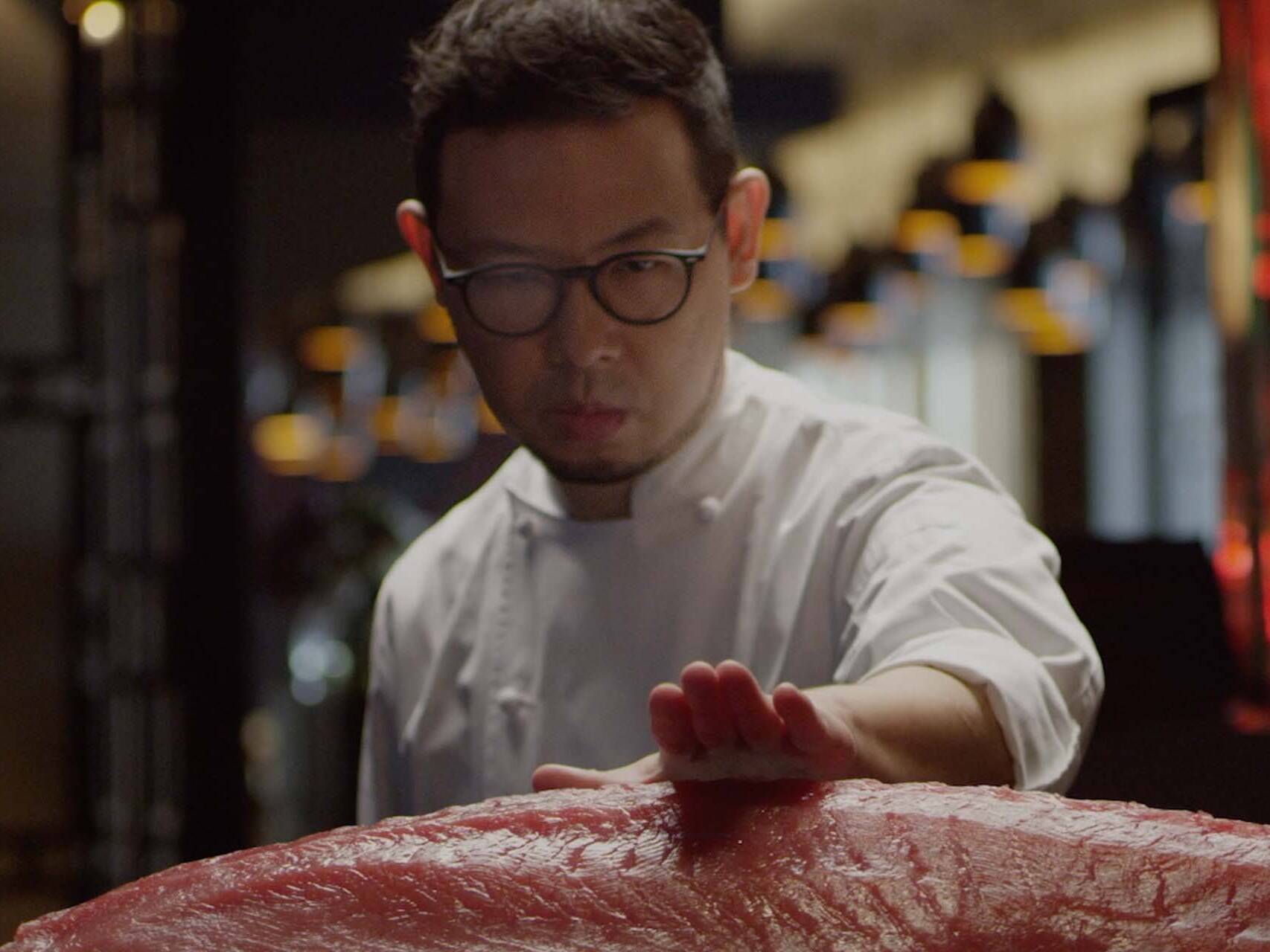 A chef demonstrating precision whilst sizing up a piece of Tuna
