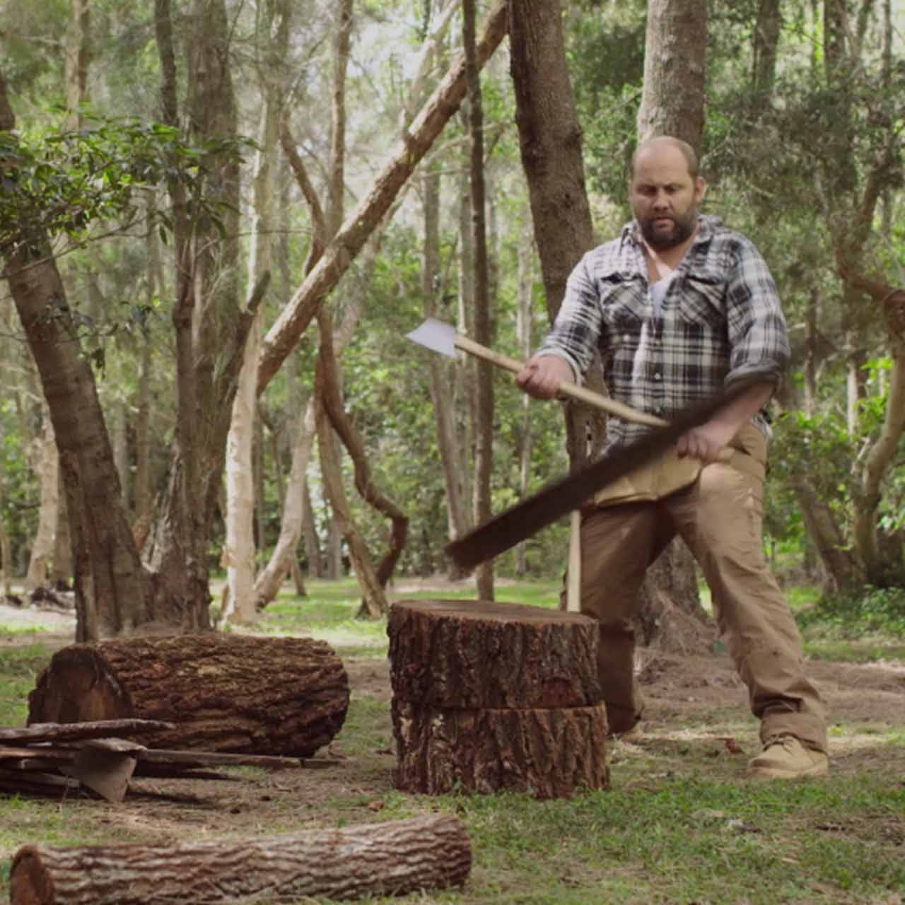 Man comically chopping wood in green riverside setting.