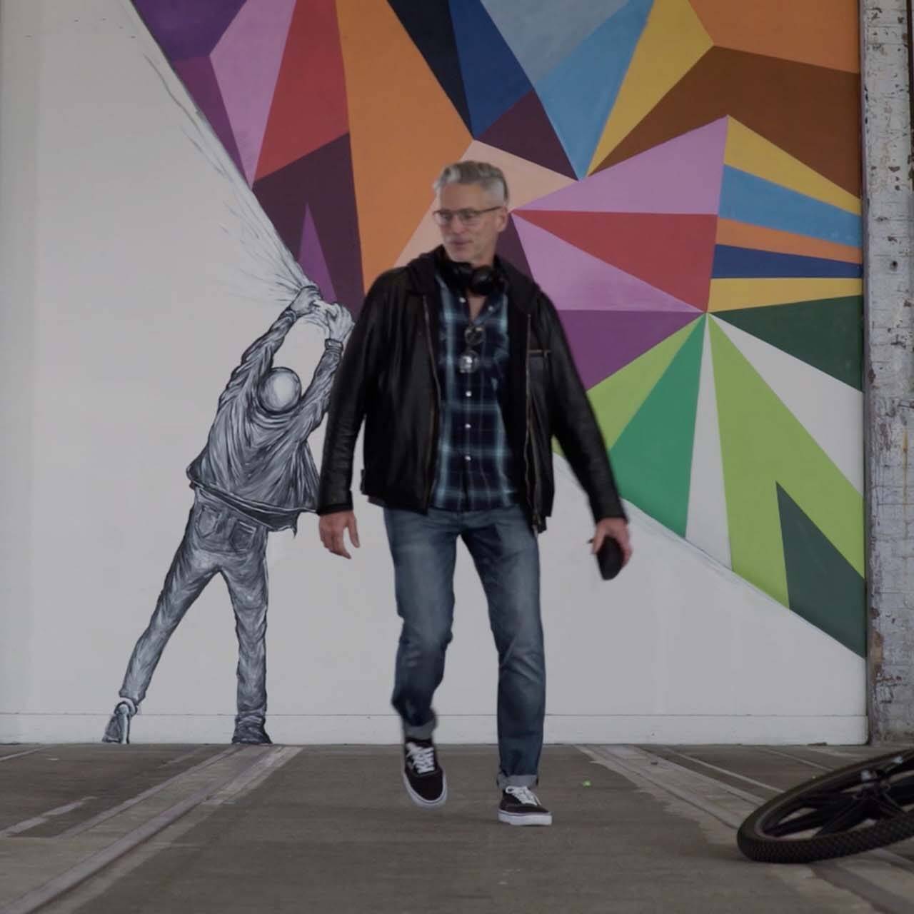 Man finishing a large graffiti mural.