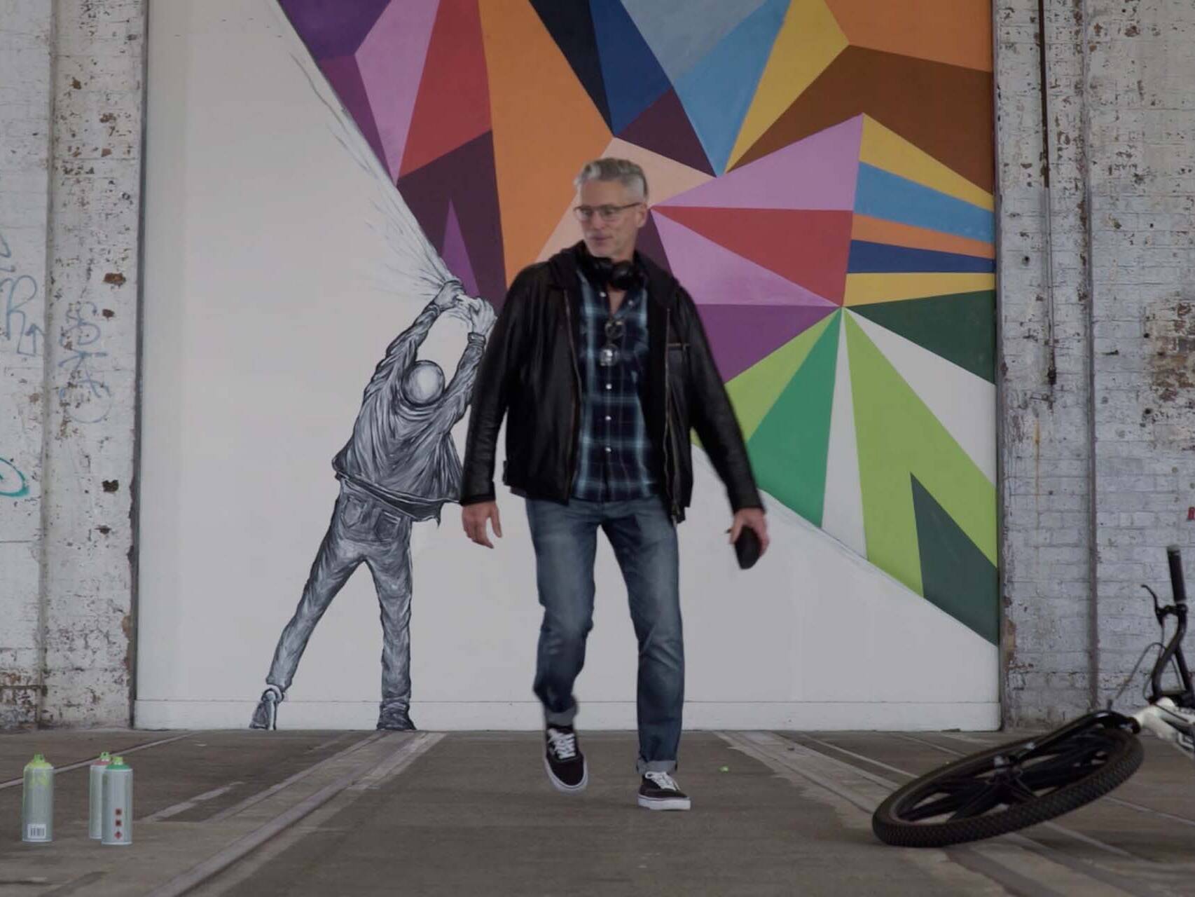 Man finishing a large graffiti mural.