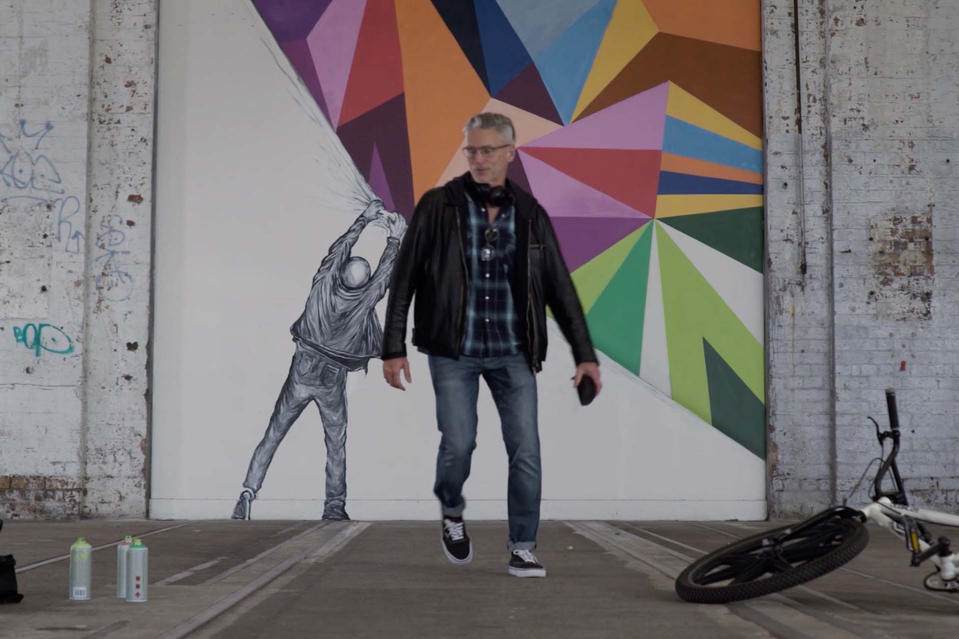 Man finishing a large graffiti mural.