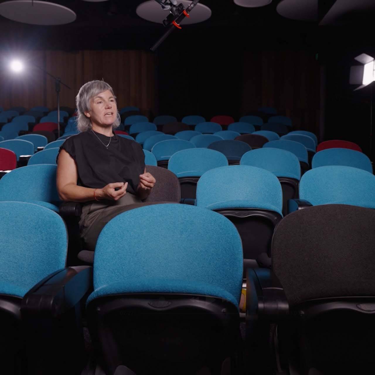 Woman sat in theatre location, surrounded by camera equipment