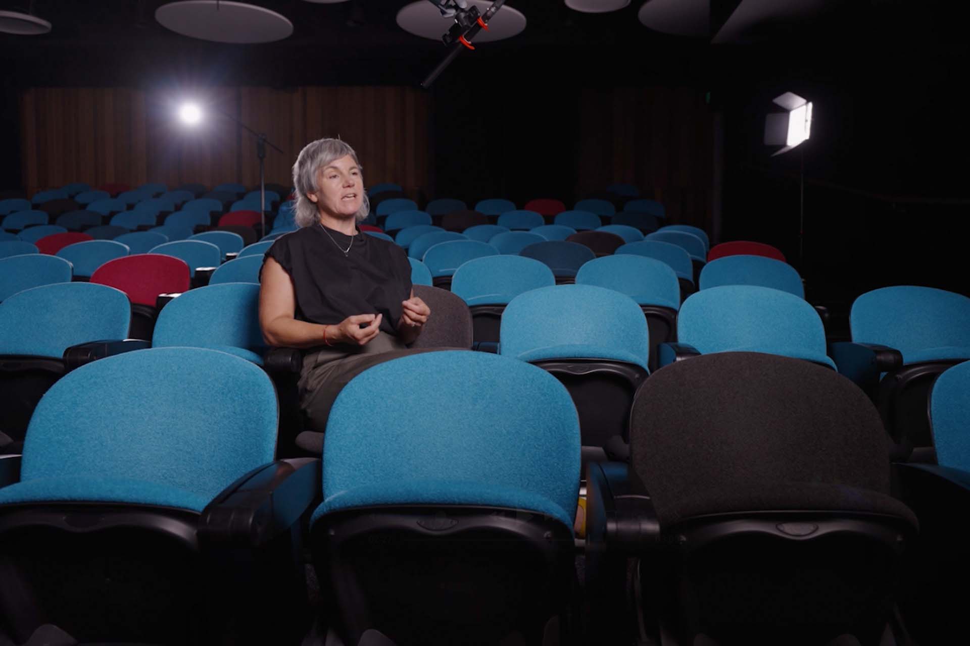 Woman sat in theatre location, surrounded by camera equipment