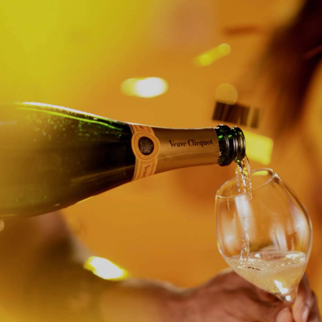 Veuve Cliquot champagne being poured in vibrant yellow setting