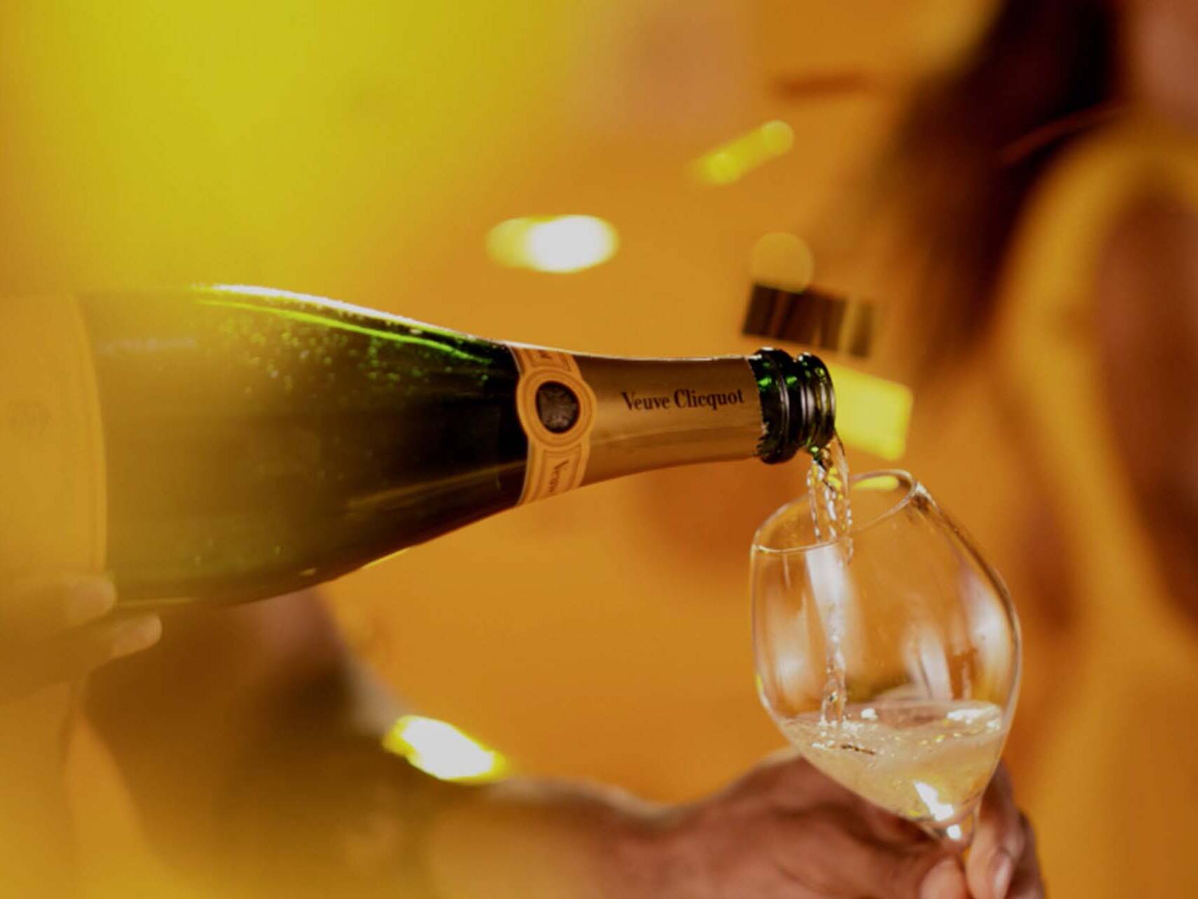Veuve Cliquot champagne being poured in vibrant yellow setting