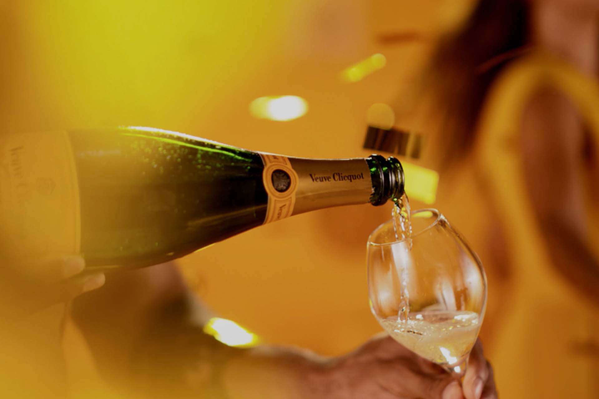 Veuve Cliquot champagne being poured in vibrant yellow setting