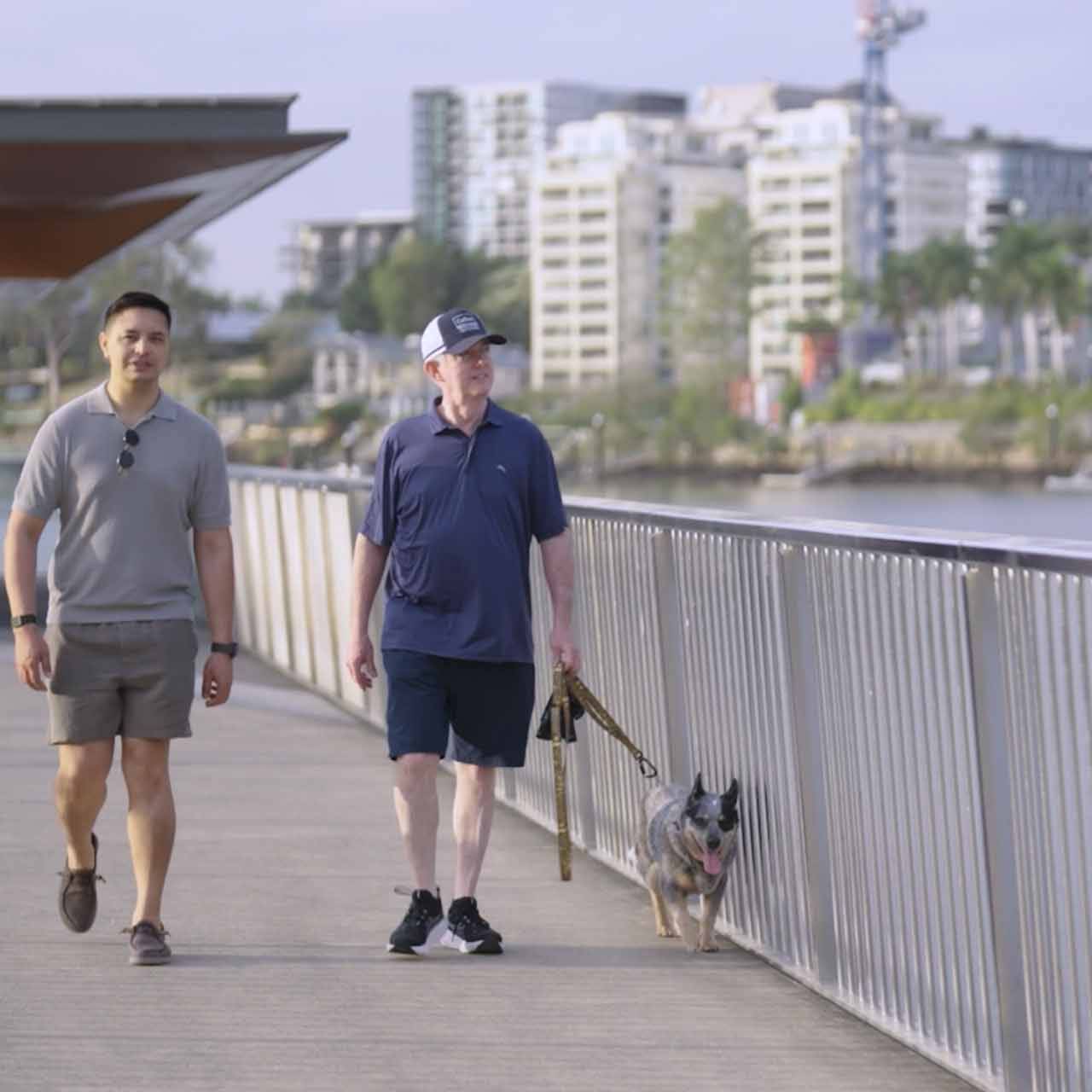 Two men walking a dog in Brisbane