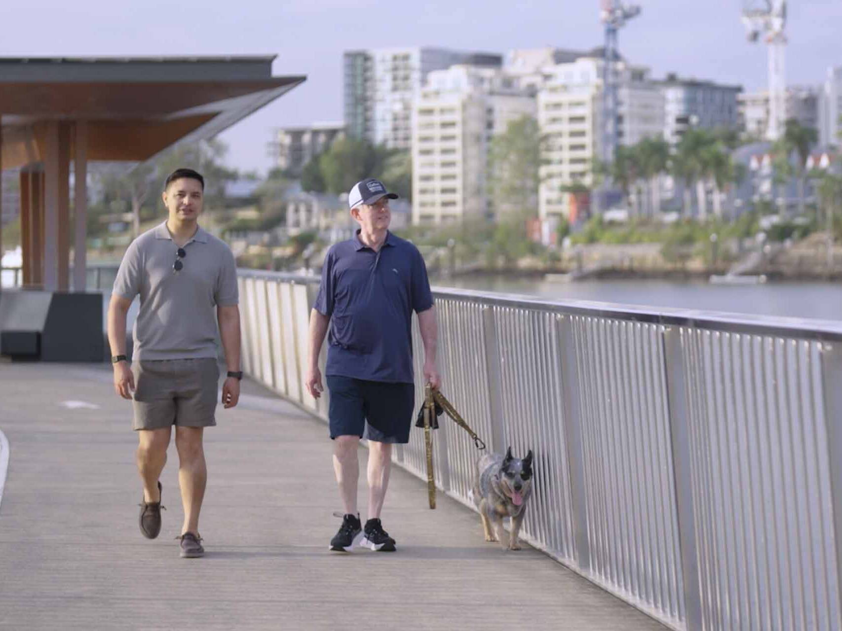 Two men walking a dog in Brisbane